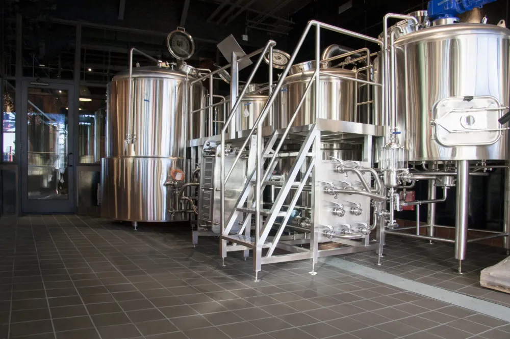 Commercial brewery production facility featuring dark grey heavy-duty quarry floor tile and stainless steel brewing equipment.