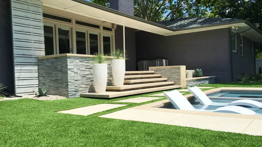Modern backyard pool patio with gray stacked stone cladding, outdoor steps, planters, and large-format pavers.