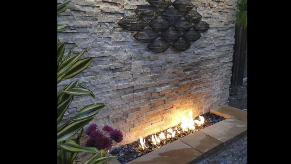 Outdoor fireplace feature wall with latte-toned ledgestone cladding and fire feature.