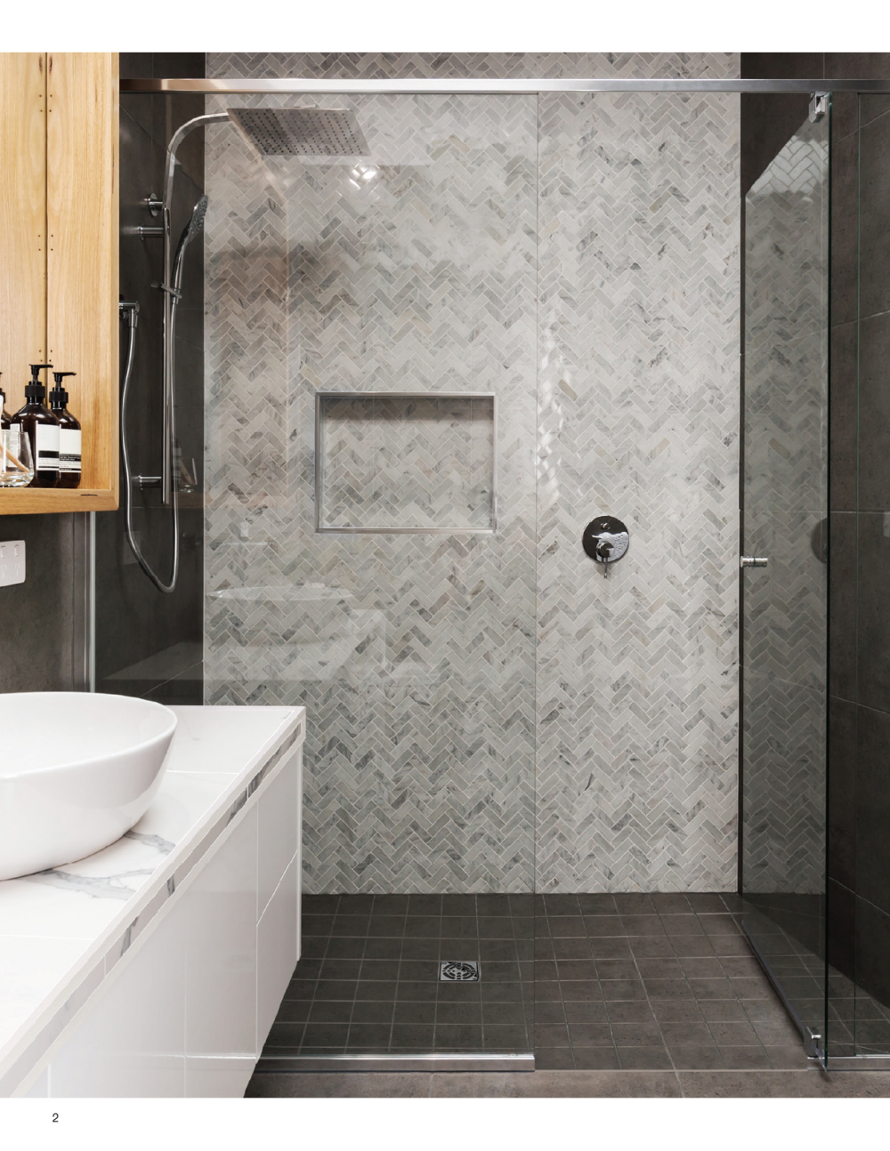 Curbless Shower System by Schluter.  Level entry grey floor shower surround in grey herringbone tile with glass door.