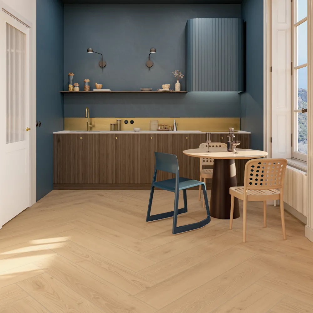 Modern kitchen floor featuring Forestal Natural blonde wood-look porcelain planks installed in a herringbone pattern alongside blue walls and a round dining table.