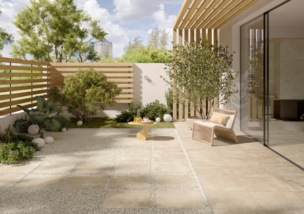 Modern outdoor patio featuring Haven Oat 24x48 beige stone-look porcelain pavers transition seamlessly from interior living room to exterior garden.