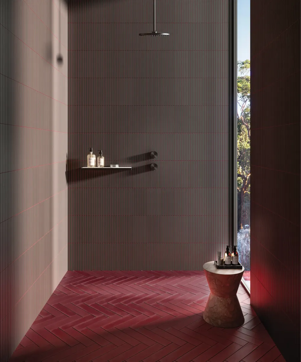 Walk-in shower featuring Spark Black Kit Kat vertically stacked mosaic wall tile contrasted with a dark red brick-look herringbone tile floor.