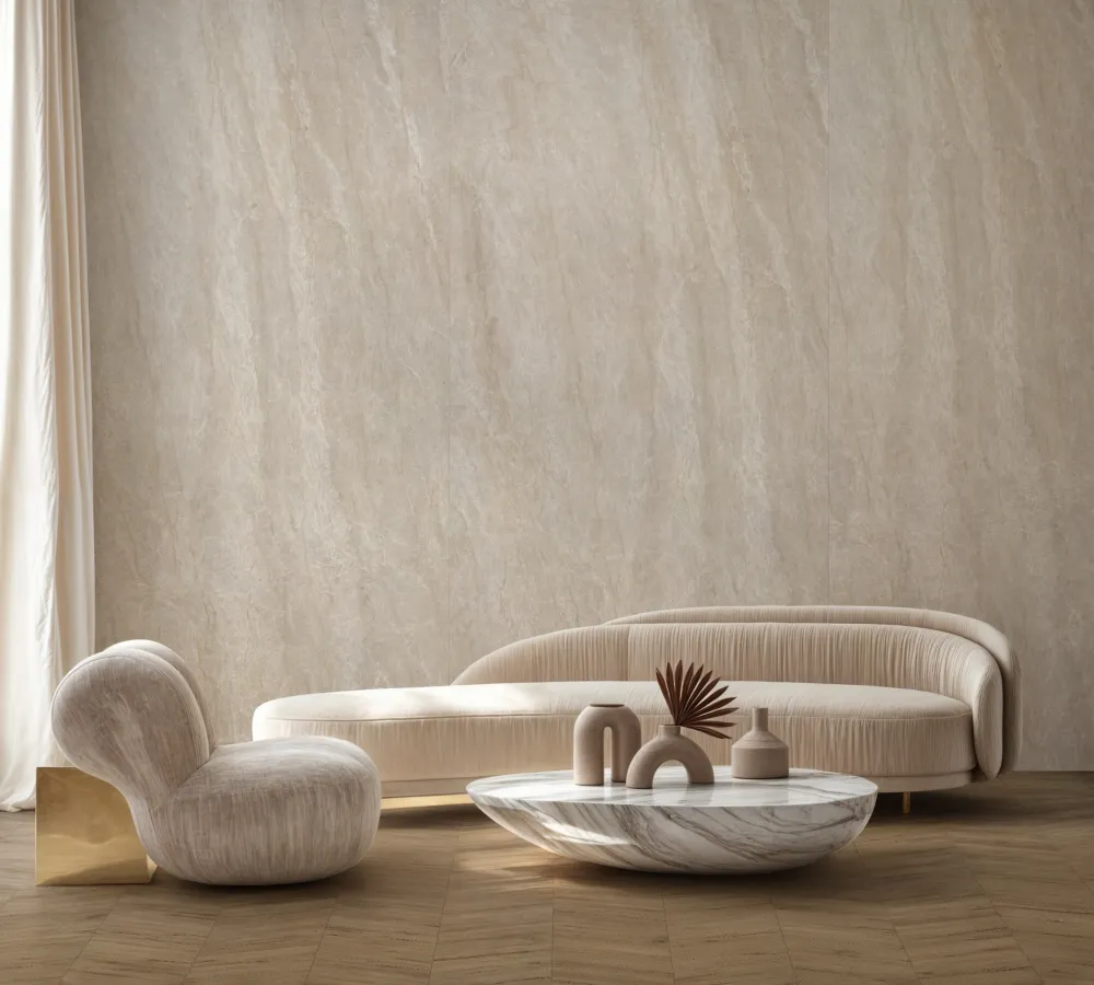 Luxury living room featuring floor-to-ceiling Majestic Caramel 24x48 porcelain slab accent walls paired with chevron wood floors and curved beige velvet lounge chairs.