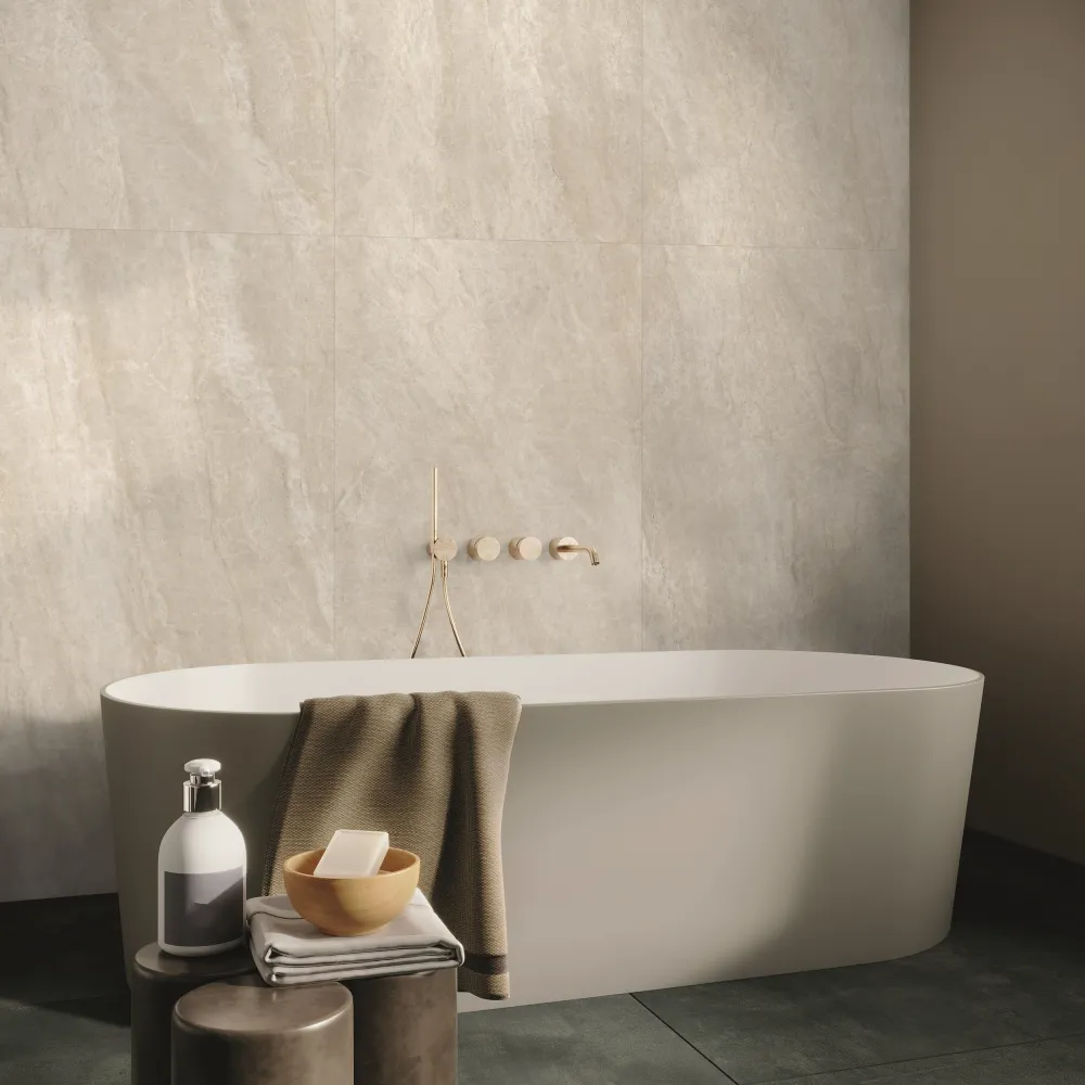 Luxury bathroom featuring Majestic Pearl stone-look porcelain wall tiles installed behind a freestanding tub with wall-mounted brass hardware.