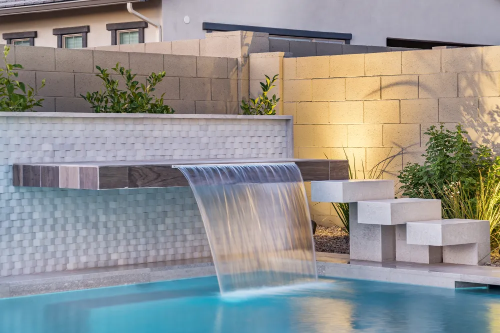Outdoor pool water feature with Crystal White New Wave dimensional wall tile and waterfall detail.