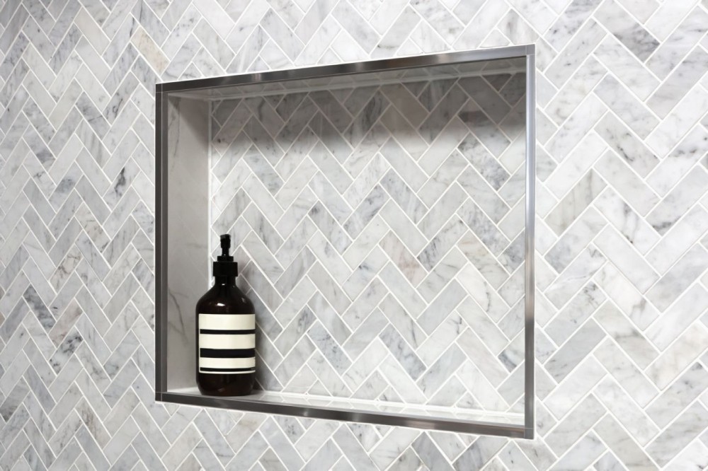 Schluter Niche and trim with herringbone tile in a shower.