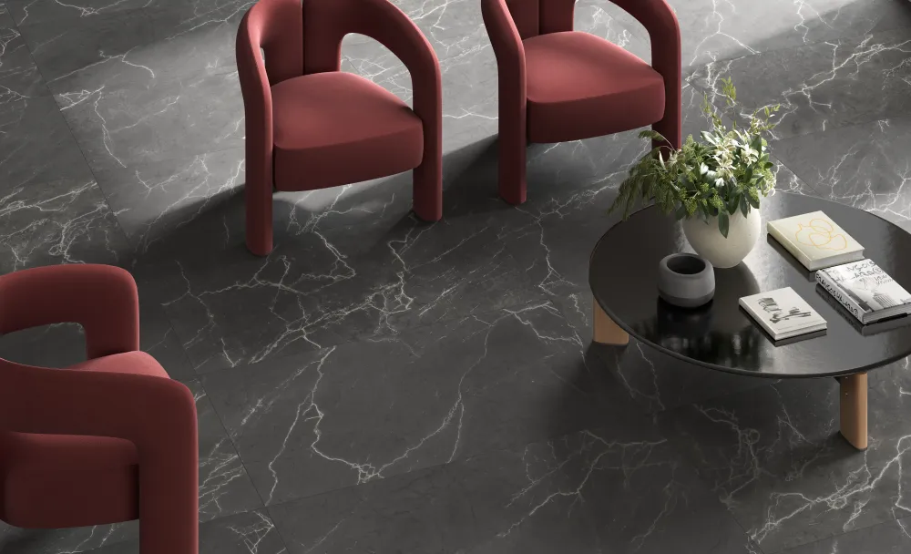Modern living room floor featuring dark charcoal marble-look large-format porcelain tile with striking white veining and red accent chairs.