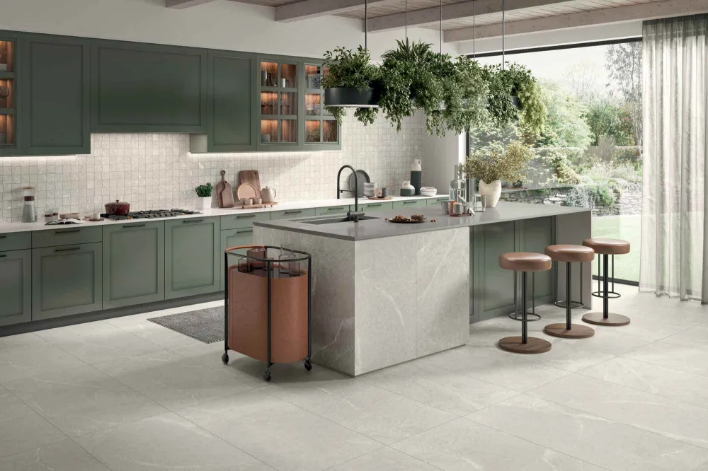 Modern kitchen clad in Select Dolomite White stone-look porcelain floor tiles and matching mosaic backsplash tile behind olive-green cabinets.