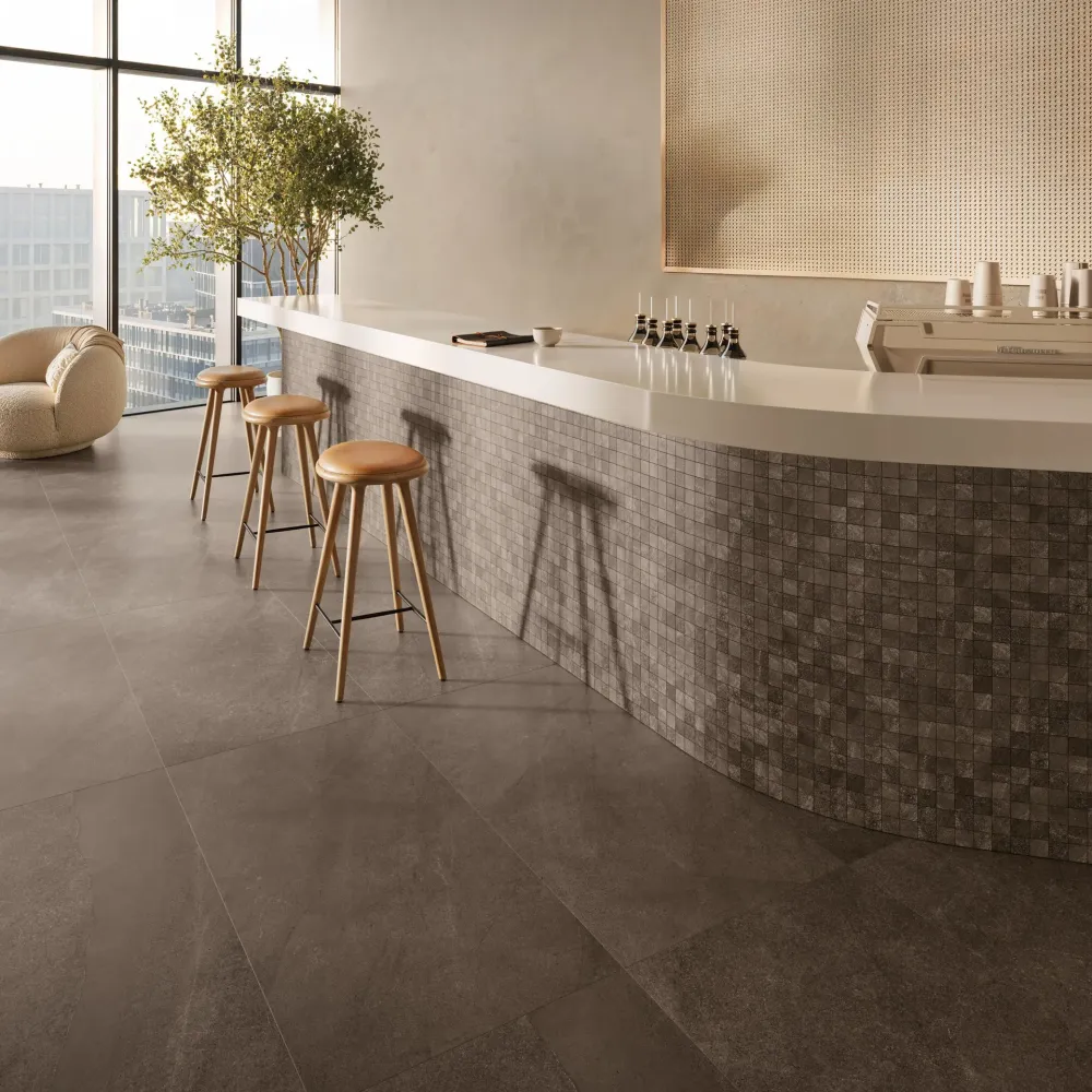Modern commercial space featuring Mocha Natural large-format stone-look floor tiles and a curved bar clad in matching square mosaic tiles.