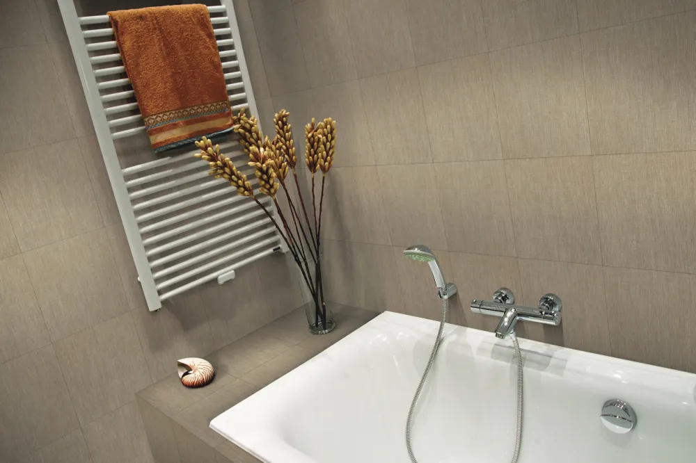 Bathroom tub surround clad in Touch Evening Sunset matte taupe linen-look tile behind a drop-in bathtub and chrome faucet.