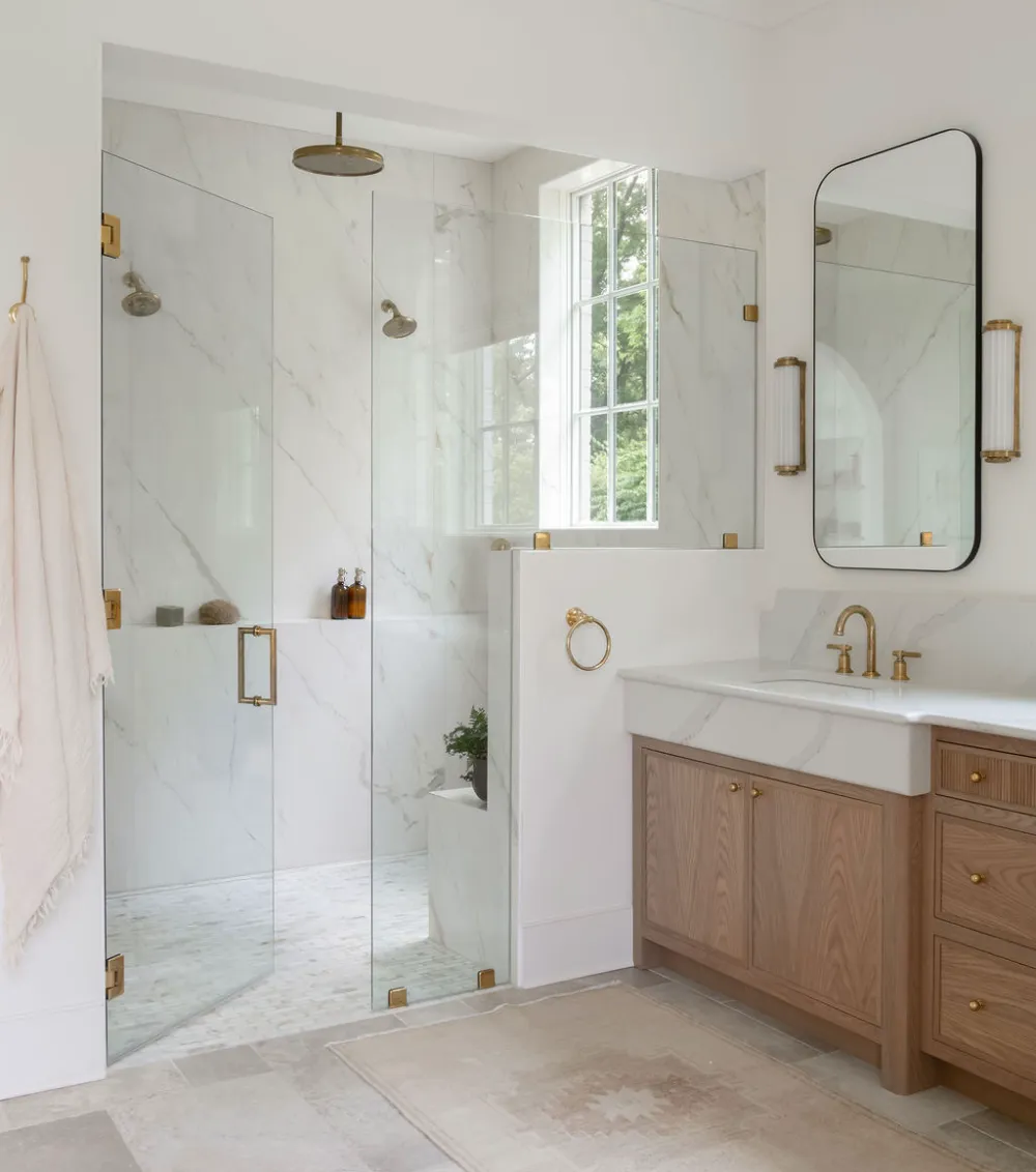 Luxury walk-in shower interior featuring Plane 2.0 large-format white marble-look porcelain panels on the walls and a matching built-in shower bench.